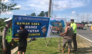 Anggota Satlantas Polres Bintan saat memasang Spanduk Himbauan dan Peringatan Rawan Kecelakaan Lalu Lintas disalah satu titik jalan Bintan