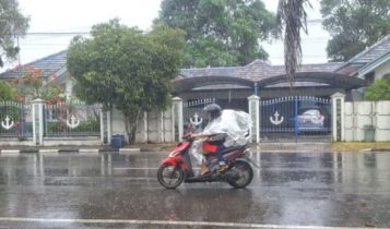 Salah seaorang warga saat menerobos Hujan menggunakan motor dan mantel untuk mengantarkan anakanya di Tanjungpinang