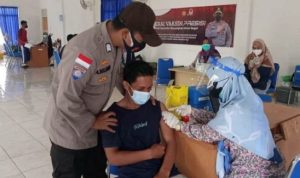 Anggota Polisi dari Polres Bintan saat membantu anak remaja melaksanakan Vaksinasi dalam Progranm Nasikapau Polres Bintan di desa Mantang Bintan