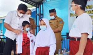 Plt Bupati Bintan memakaikan seragam sekolah kepada siswa.