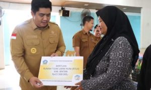 Bupati Bintan Roby Kurniawan saat menyerahkan secara simbolis anggaran dana Program RTLH APBD Bintan pada masyarakat poenerima di Bntan