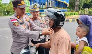Kapolsek Bintan Timur, AKP Rugianto membagikan helm gratis ke pengendara motor di depan Bundaran Tugu Tanjak, Kijang Kota Kecamatan Bintan Timur, Selasa (6/6/2023). (Foto: Hasura/Presmedia)