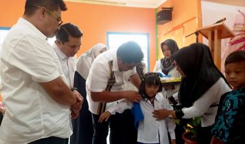 Bupati Bintan Roby Kurniawan saat memakaikan secara simbolis baju sekolah anak TK di Aula SDN 03 Bintan Timur. (Foto: Diskomifo Bintan)