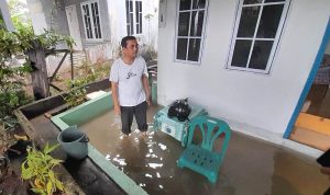 Salah seorang warga Kampung Kolam Tanjungpinang, membersihkan air dari dalam rumahnya setelah dilanda banjir akibat hujan lebat melanda kota Tanjungpinang (Roland/Presmedia.id)