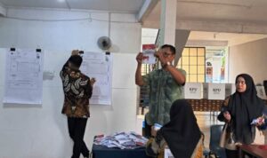 Ketua KPPS TPS 038 Natal Fredi menghitung surat suara. (Foto: Hasura/Presmedia.id)