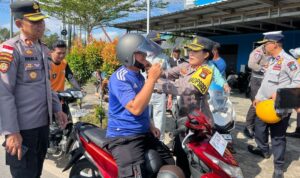 Kapolres Bintan AKBP Yunita Stevani didampingi Kasat Lantas AKP Firuddin membagikan helm gratis kepada pengendara motor di Jalan Raya Km 16 Desa Toapaya Selatan. (Foto: Hasura/Presmedi.id)