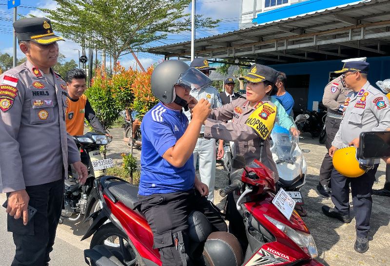 Kapolres Bintan AKBP Yunita Stevani didampingi Kasat Lantas AKP Firuddin membagikan helm gratis kepada pengendara motor di Jalan Raya Km 16 Desa Toapaya Selatan. (Foto: Hasura/Presmedi.id)