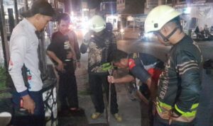 Personil UPT Damkar Bintan Utara membantu mengambilkan kunci motor milik warga Tanjung Uban yang masuk ke dalam selokan dengan penjepit ular. (Foto Damkar Bintan)