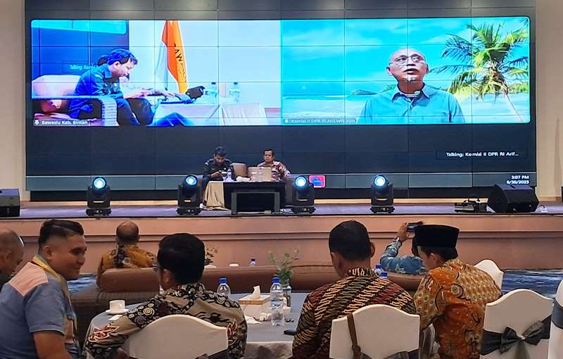 Komisioner Bawaslu Bintan, KPU Bintan serta seluruh undangan mendengarkan penyampaian Anggota Komisi II DPR RI Arif Wibowo via Zoom di Aula Agro Resorts Km 36 Kecamatan Gunung Kijang. (Foto Hasura)